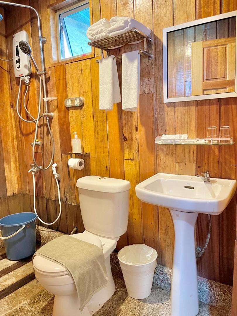 A well-lit bathroom at Nusakuya Resort with modern white washbasin, wide vanity mirror and natural light.
