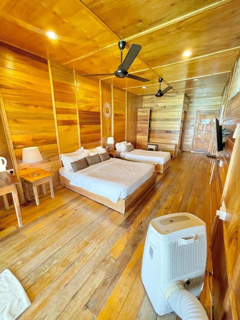 A spacious bedroom at Nusakuya Resort over the water featuring two comfortable beds, classic timber cladding with beautiful wooden floors, and air conditioning.